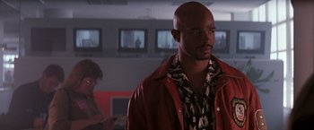 Movie still from “The Last Boy Scout” (1991), directed by Tony Scott – A man in a red jacket standing next to another man; Medium shot, Low angle