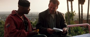Movie still from “The Last Boy Scout” (1991), directed by Tony Scott – Two men sitting on a bench looking at a piece of paper; Medium shot, Over the shoulder angle