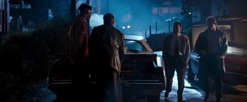 Movie still from “The Last Boy Scout” (1991), directed by Tony Scott – A group of men standing next to each other near a car at night; Wide shot, Over the shoulder angle