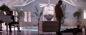 Movie still from “The Last Boy Scout” (1991), directed by Tony Scott – A man standing next to a chair in a room; Wide shot, Low angle