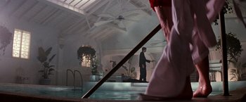 Movie still from “The Last Boy Scout” (1991), directed by Tony Scott – A man standing next to a pool in a room; Wide shot, Low angle