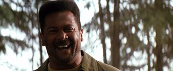 Movie still from “The Last Boy Scout” (1991), directed by Tony Scott – A person smiling with trees in the background; Close Up shot, Low angle