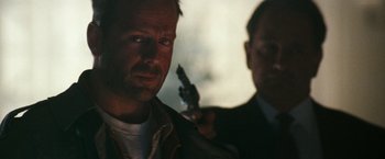 Movie still from “The Last Boy Scout” (1991), directed by Tony Scott – A man holding a gun next to another man in a suit; Close Up shot, Low angle