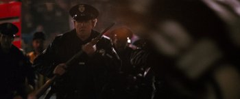 Movie still from “The Last Boy Scout” (1991), directed by Tony Scott – A police officer holding a gun while standing next to another officer; Medium shot, Over the shoulder angle