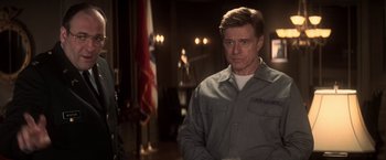 Movie still from “The Last Castle” (2001), directed by Rod Lurie – A man standing in front of an american flag in a room; Medium shot, Over the shoulder angle