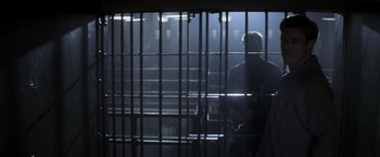 Movie still from “The Last Castle” (2001), directed by Rod Lurie – A man standing behind bars in a jail cell at night; Wide shot, Low angle