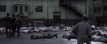Movie still from “The Last Castle” (2001), directed by Rod Lurie – A group of people laying on the ground in the street; Wide shot, High angle