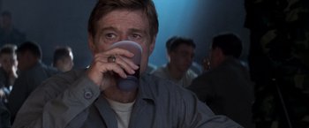 Movie still from “The Last Castle” (2001), directed by Rod Lurie – A man drinking from a cup in front of other men; Close Up shot, Over the shoulder angle