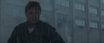 Movie still from “The Last Castle” (2001), directed by Rod Lurie – A man standing in the middle of the street in the pouring rain; Medium shot, Low angle