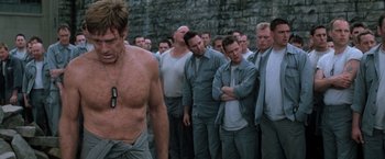 Movie still from “The Last Castle” (2001), directed by Rod Lurie – A group of men standing next to each other in front of a brick wall; Medium shot, Low angle