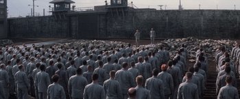 Movie still from “The Last Castle” (2001), directed by Rod Lurie – A large group of men in grey suits standing in front of a wall; Extreme Wide shot, High angle