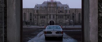 Movie still from “The Last Castle” (2001), directed by Rod Lurie – A car parked in front of an old building with an american flag; Extreme Wide shot, Low angle