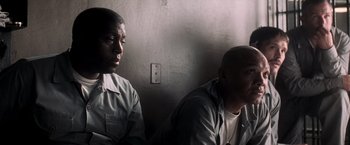 Movie still from “The Last Castle” (2001), directed by Rod Lurie – A couple of men sitting next to each other in front of a wall; Medium shot, High angle