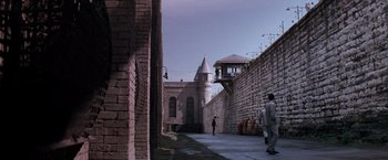 Movie still from “The Last Castle” (2001), directed by Rod Lurie – Two men walking down a brick walkway next to a brick wall; Extreme Wide shot, High angle