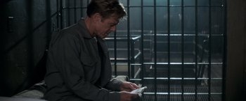 Movie still from “The Last Castle” (2001), directed by Rod Lurie – A man reading a book in a jail cell; Medium shot, High angle