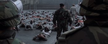 Movie still from “The Last Castle” (2001), directed by Rod Lurie – A group of people laying on the ground in the middle of the street; Wide shot, High angle
