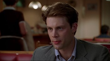 Movie still from “The Last Days of Disco” (1998), directed by Whit Stillman – A man in a gray jacket and a white shirt; Close Up shot, Over the shoulder angle