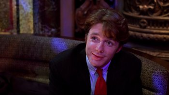 Movie still from “The Last Days of Disco” (1998), directed by Whit Stillman – A man wearing a suit and red neck tie; Close Up shot, Over the shoulder angle