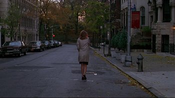 Movie still from “The Last Days of Disco” (1998), directed by Whit Stillman – A woman walking down a street in a trench coat; Wide shot, Low angle