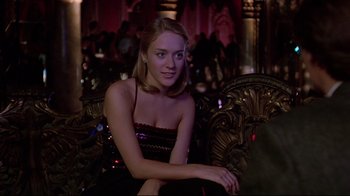 Movie still from “The Last Days of Disco” (1998), directed by Whit Stillman – A beautiful young lady sitting on a couch in a room; Medium shot, Over the shoulder angle