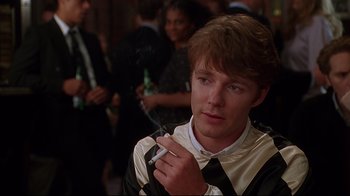 Movie still from “The Last Days of Disco” (1998), directed by Whit Stillman – A young man smoking a cigarette in front of a group of people; Close Up shot, Over the shoulder angle