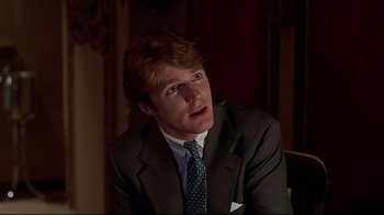 Movie still from “The Last Days of Disco” (1998), directed by Whit Stillman – A man wearing a suit and tie sitting in a room; Close Up shot, Over the shoulder angle