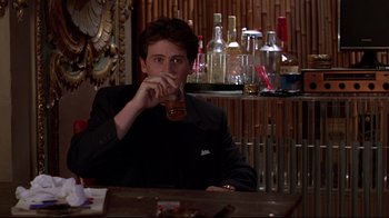 Movie still from “The Last Days of Disco” (1998), directed by Whit Stillman – A man sitting at a table drinking a beer; Medium shot, Low angle
