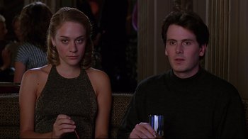 Movie still from “The Last Days of Disco” (1998), directed by Whit Stillman – A man and a woman sitting next to each other holding drinks; Medium shot, Low angle