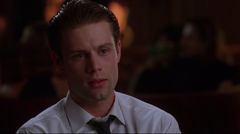 Movie still from “The Last Days of Disco” (1998), directed by Whit Stillman – A man wearing a white dress shirt and a tie; Close Up shot, Over the shoulder angle