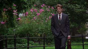 Movie still from “The Last Days of Disco” (1998), directed by Whit Stillman – A man in a suit and tie standing in front of flowers; Medium shot, Low angle