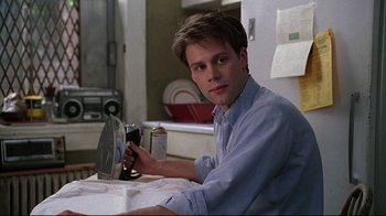 Movie still from “The Last Days of Disco” (1998), directed by Whit Stillman – A man sitting at a table with a bottle of beer; Close Up shot, Low angle