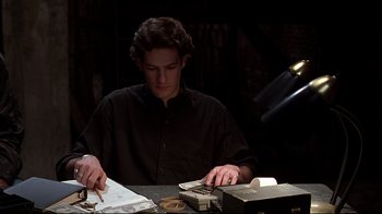 Movie still from “The Last Days of Disco” (1998), directed by Whit Stillman – A man sitting at a table looking at papers; Medium shot, High angle