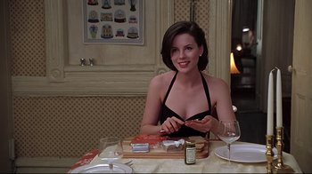 Movie still from “The Last Days of Disco” (1998), directed by Whit Stillman – A woman sitting at a dinner table cutting up meat; Medium shot, Over the shoulder angle