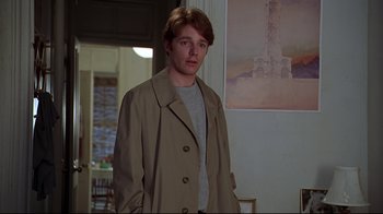 Movie still from “The Last Days of Disco” (1998), directed by Whit Stillman – A young man in a trench coat standing in front of a painting; Medium shot, Low angle