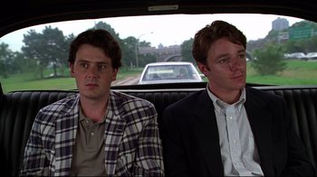 Movie still from “The Last Days of Disco” (1998), directed by Whit Stillman – Two men sitting in the back of a car next to each other; Medium shot, Low angle