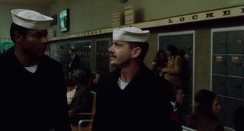 Movie still from “The Last Detail” (1973), directed by Hal Ashby – A man wearing a sailor's hat in front of a crowd of onlookers; Medium shot, Low angle