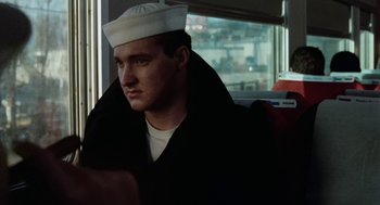 Movie still from “The Last Detail” (1973), directed by Hal Ashby – A man wearing a sailor's hat sitting on a bus; Close Up shot, Over the shoulder angle