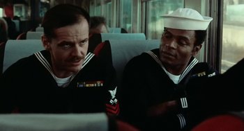 Movie still from “The Last Detail” (1973), directed by Hal Ashby – Two sailors sitting on a train looking at something on a computer screen; Close Up shot, Low angle