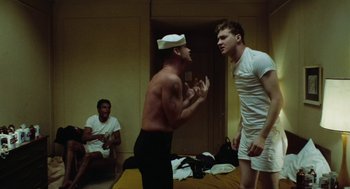 Movie still from “The Last Detail” (1973), directed by Hal Ashby – A group of men standing in a room; Medium shot, Over the shoulder angle