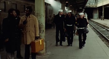 Movie still from “The Last Detail” (1973), directed by Hal Ashby – A group of men in navy uniforms walking down a train platform; Wide shot, Over the shoulder angle