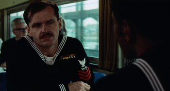 Movie still from “The Last Detail” (1973), directed by Hal Ashby – A man in a uniform sitting next to another man in a uniform; Close Up shot, Over the shoulder angle
