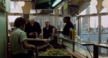 Movie still from “The Last Detail” (1973), directed by Hal Ashby – A group of men standing in a kitchen preparing food; Wide shot, High angle