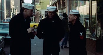 Movie still from “The Last Detail” (1973), directed by Hal Ashby – Three men in hats are standing on the sidewalk; Medium shot, Low angle