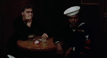 Movie still from “The Last Detail” (1973), directed by Hal Ashby – Two men sitting at a table with drinks; Medium shot, Over the shoulder angle