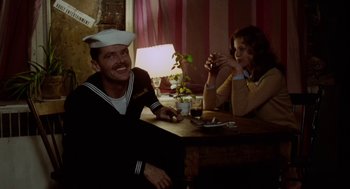 Movie still from “The Last Detail” (1973), directed by Hal Ashby – A man and a woman sitting at a wooden table; Medium shot, Over the shoulder angle
