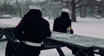 Movie still from “The Last Detail” (1973), directed by Hal Ashby – A couple of people sitting at a picnic table in the snow; Wide shot, Low angle