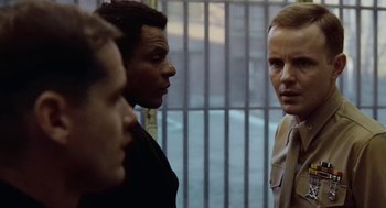 Movie still from “The Last Detail” (1973), directed by Hal Ashby – A group of men standing next to each other in front of a fence; Close Up shot, Over the shoulder angle