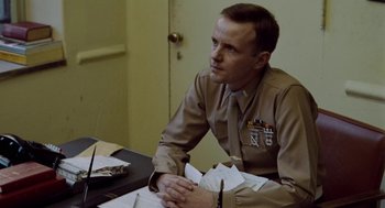 Movie still from “The Last Detail” (1973), directed by Hal Ashby – A man sitting at a table with papers in front of him; Medium shot, Low angle