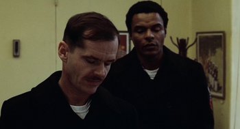 Movie still from “The Last Detail” (1973), directed by Hal Ashby – Two men in black shirts are looking down at one of them; Close Up shot, Over the shoulder angle