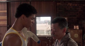 Movie still from “The Last Dragon” (1985), directed by Michael Schultz – A man and a young man are talking in a room; Medium shot, Over the shoulder angle